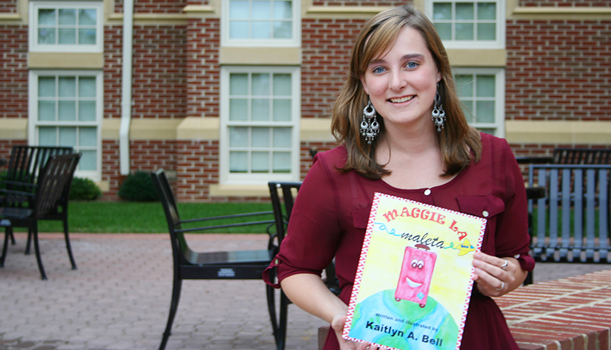 Kaitlyn Bell holding her book, "Maggie La Maleta"